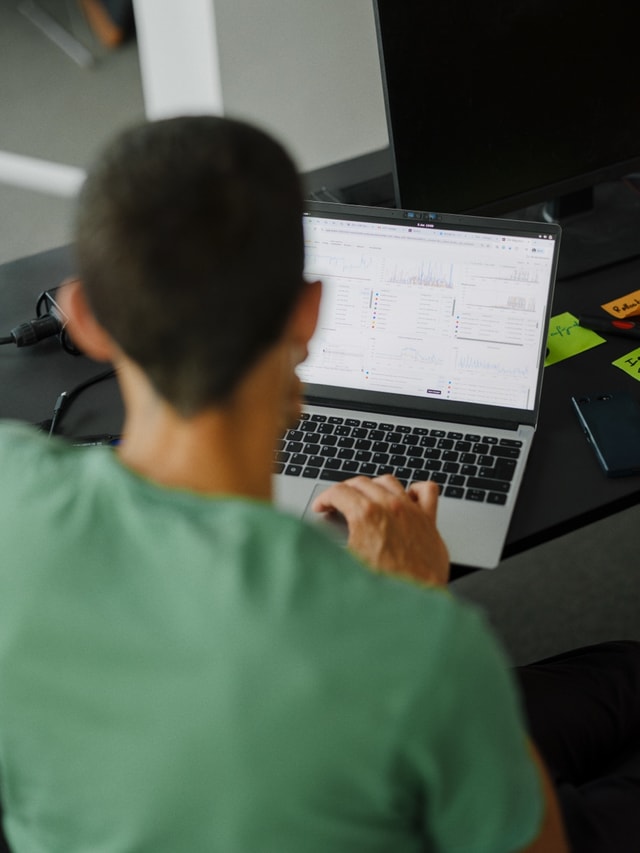 A teammate in a green shirt working at a laptop