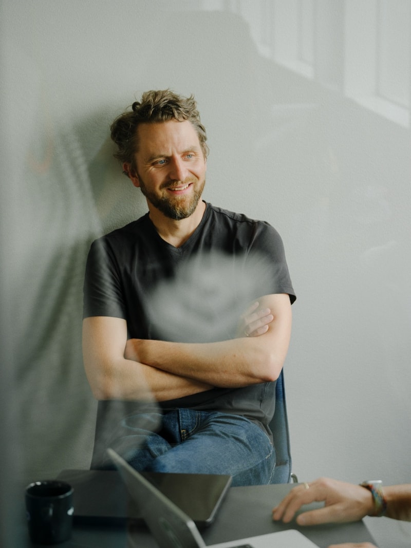An engineer leaning back, arms crossed, in a sunlit office