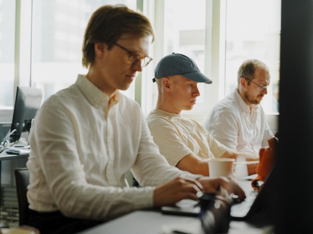 Three colleagues gathered around a desk, working through a problem together