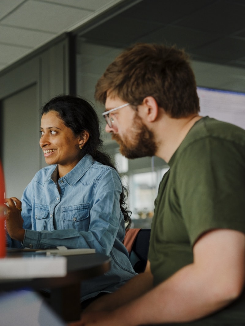 Two colleagues in conversation across a desk