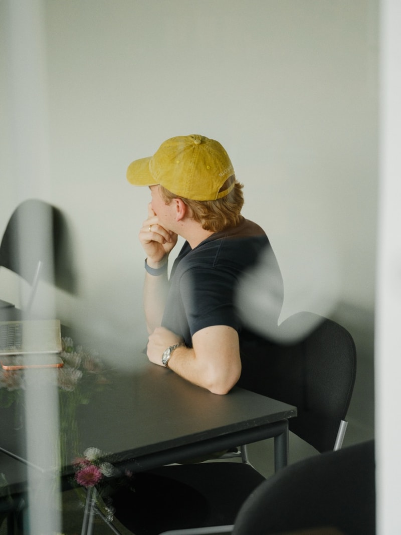 A teammate in a yellow beanie, lit by warm window light