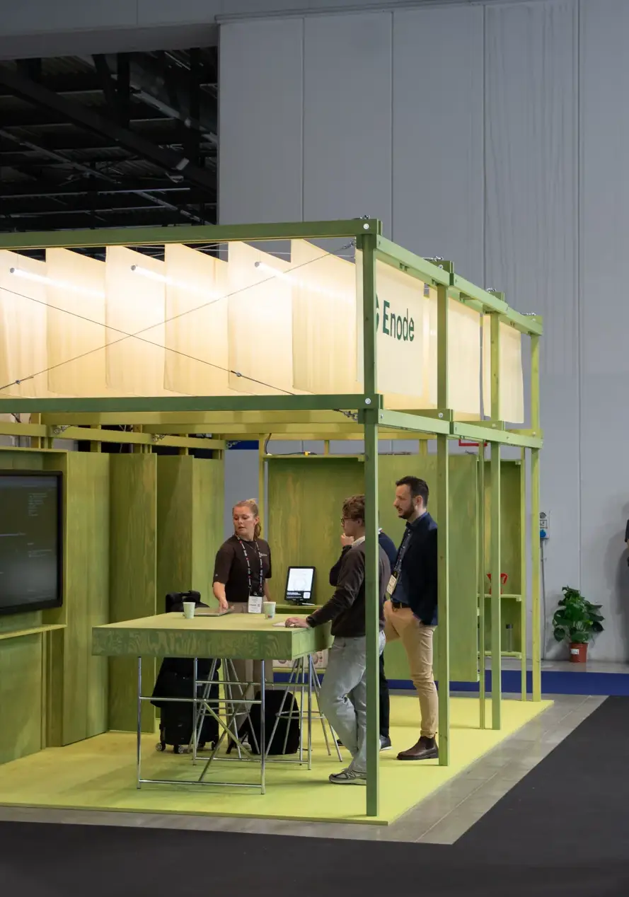 The Enode stand on the conference floor, its green timber frame open to visitors as the team talks with attendees